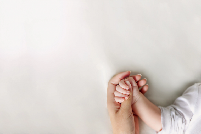 A close-up of a mother's hand holding a young child's hand