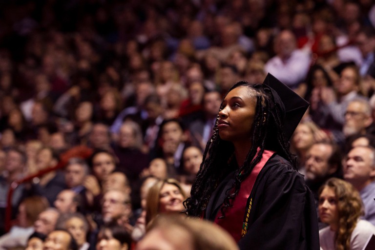 A woman stands among the crowd at graduation.