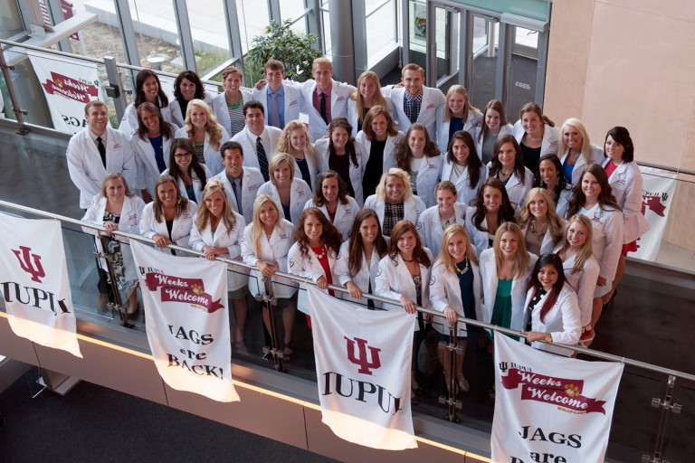 Physician assistant program students stand in a group wearing white coats