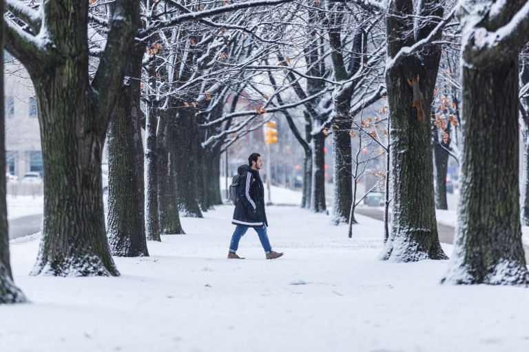 A student walking through the snow on campus