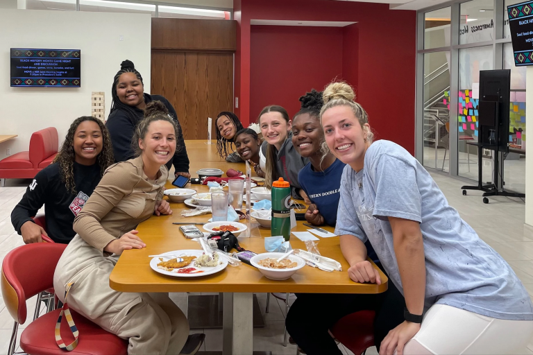 A group of student-athletes eat a meal at a table
