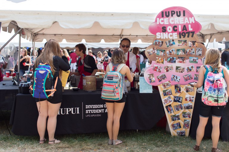IUPUI staff members serve ice cream to students underneath a giant tent.