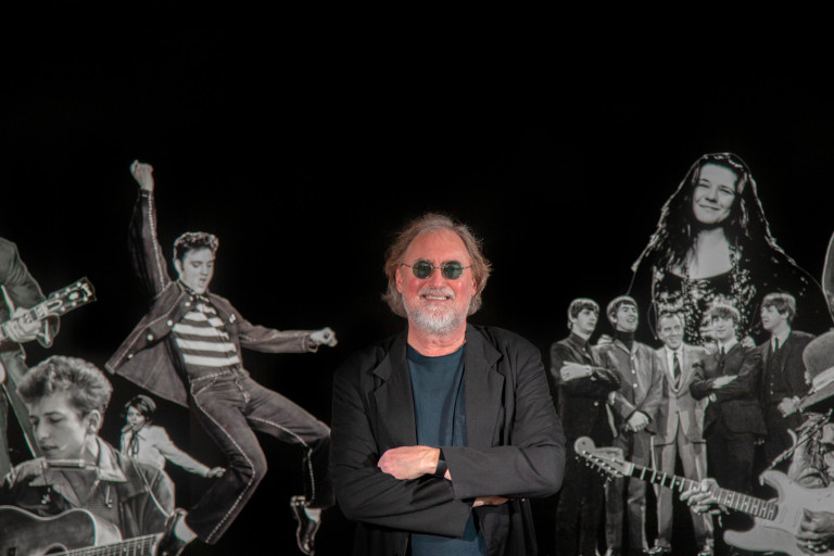 Glenn Gass with images of rock stars behind him