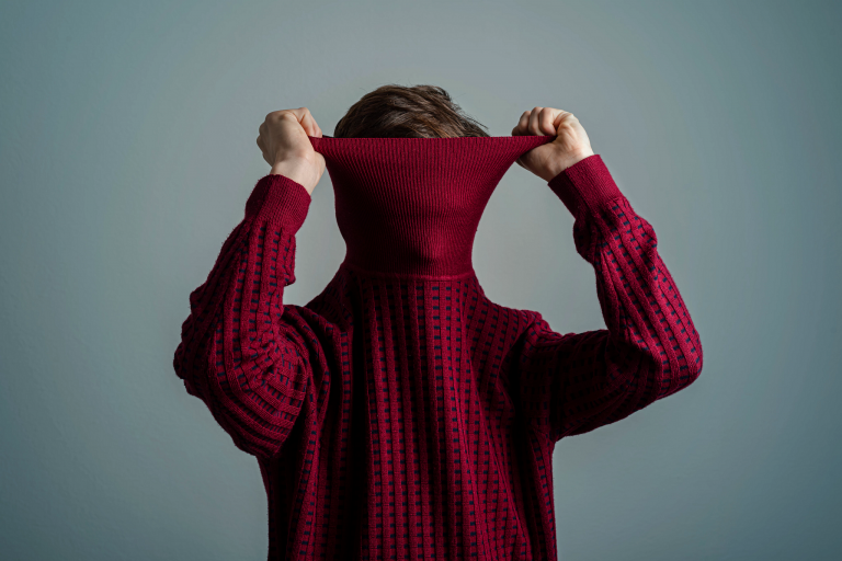 a person pulling a red sweater over their head