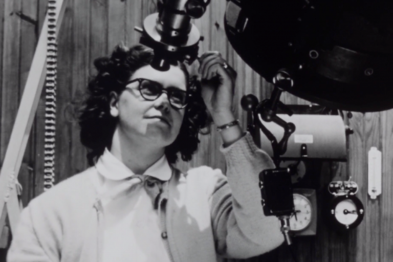 A woman looks into a telescope