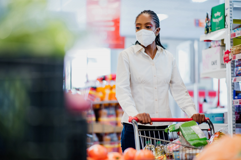 A woman wearing a KN95 mask pushes a grocery cart