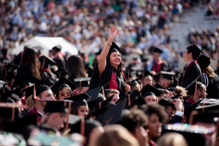 Graduate waves to crowd at commencement ceremony in May 2016