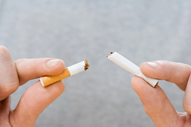 Closeup of two hands breaking a cigarette in half