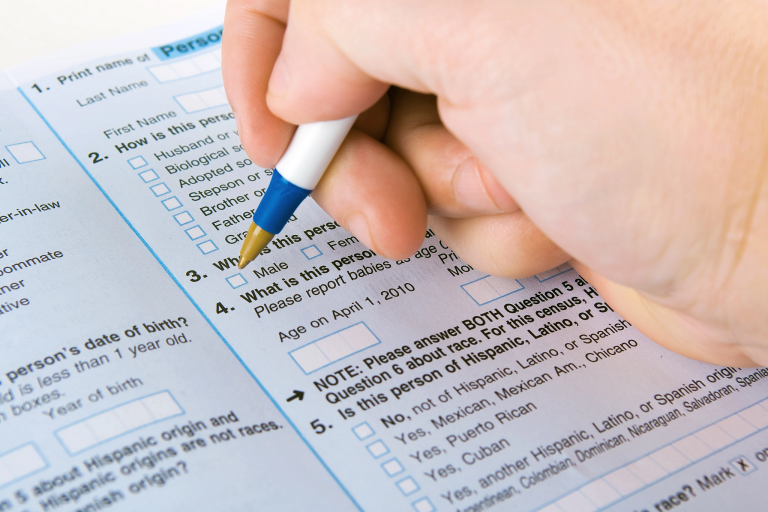 A hand holding a pen to fill out a U.S. Census form