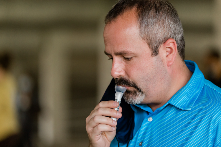 A man takes a mitigation test for COVID-19 by spitting into a tube