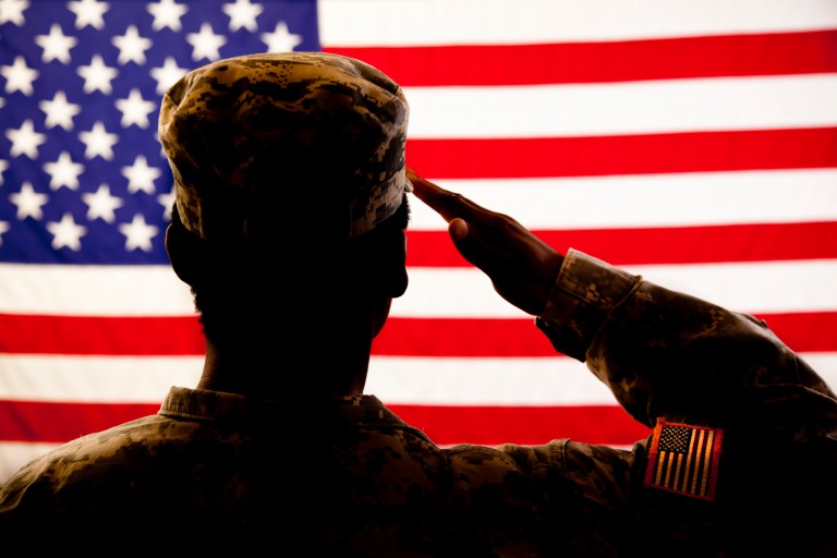A soldier salutes the American flag.