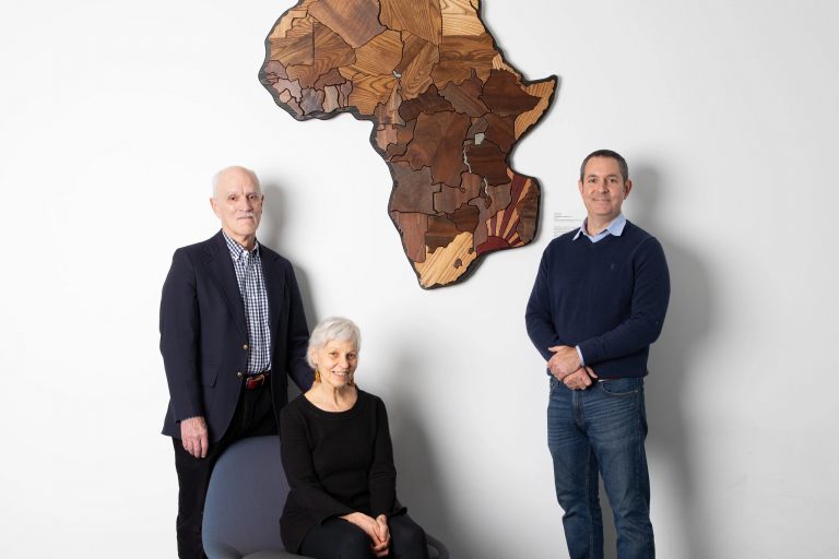 Ann Marie Thomson and Louis J. Calli Jr. stand beside a carving of the African continent