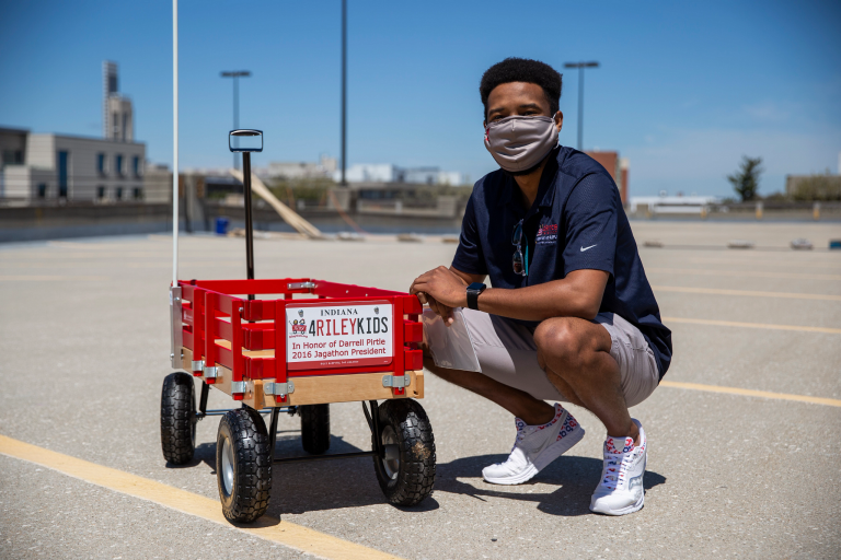 A student kneels down next to a red Riley wagon