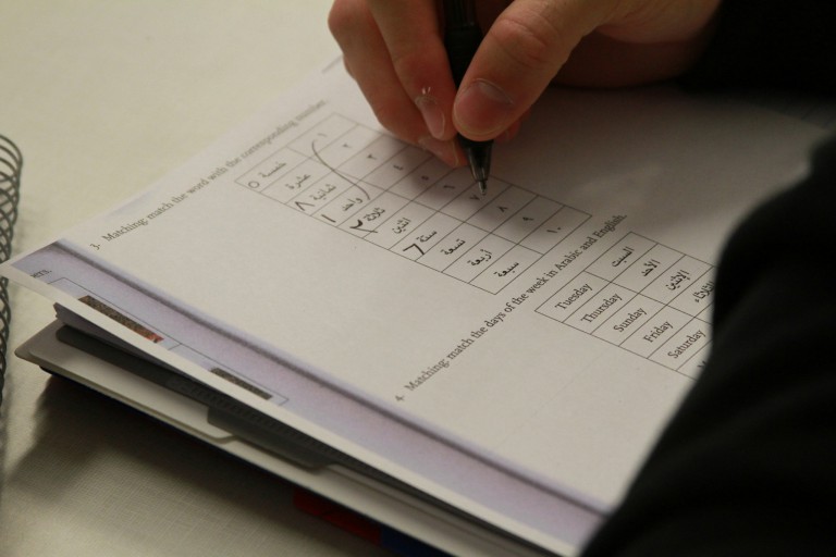 Close-up of Arabic characters being written in a workbook
