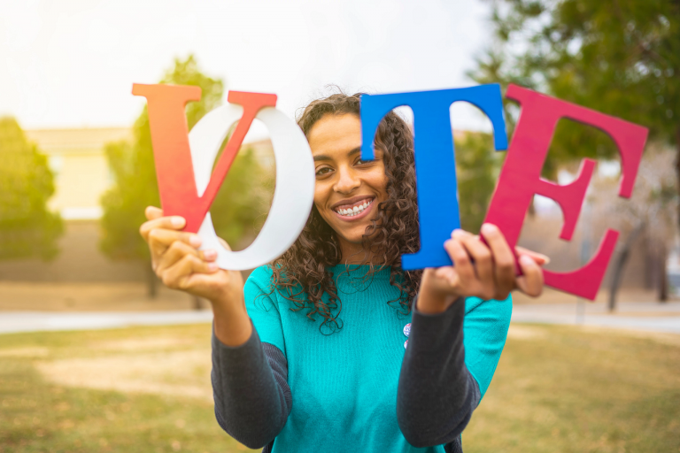 Woman holds up letters that spell "VOTE"