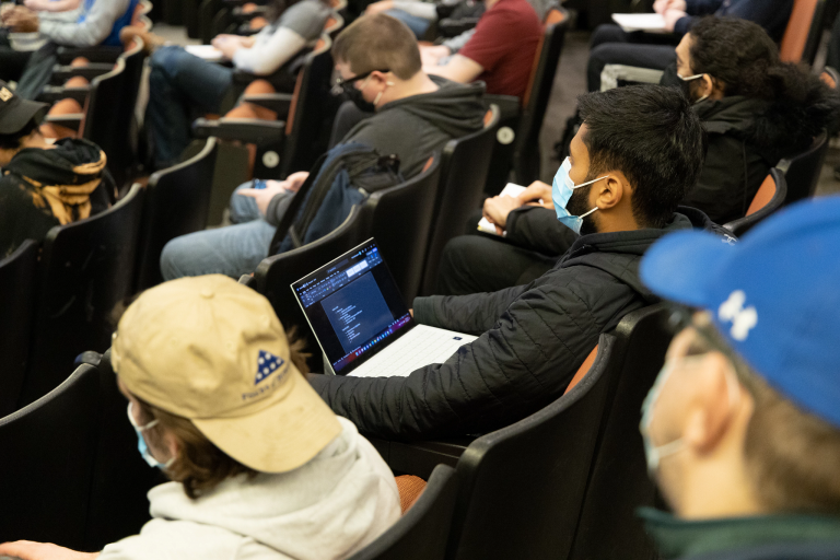 Students sitting in a lecture hall with laptops.