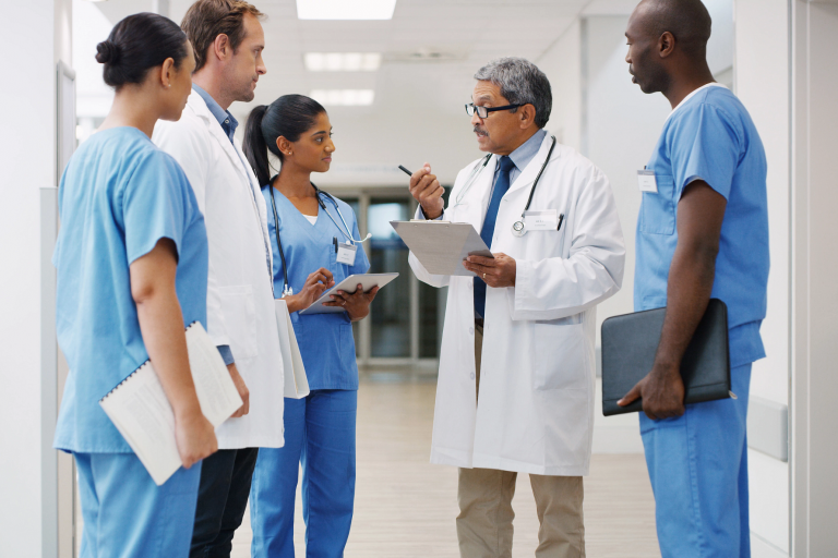 Health care workers have a group discussion in a hospital hallway