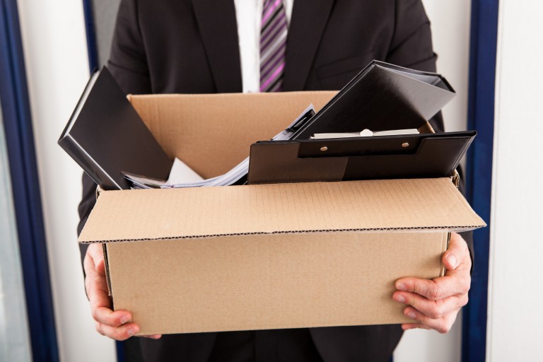 Man in suit holding a box of office supplies