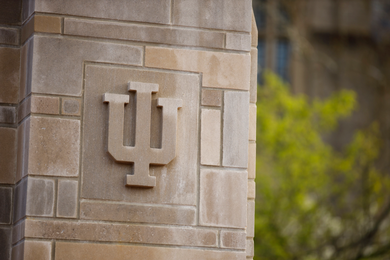 The IU trident is visible on a limestone building on the IU Bloomington campus
