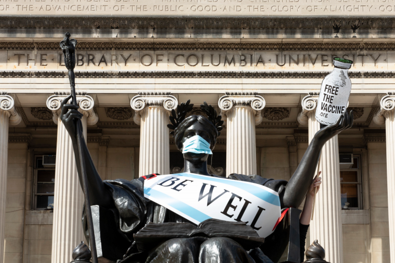 A statue by Columbia University Library wears a mask and a sign that says 'be well'