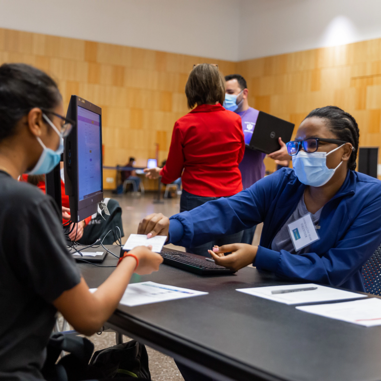 A medical person hands a card to a person who is getting vaccinated