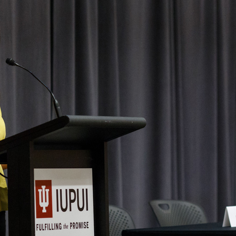 Naomi Pescovitz of WTHR stands at a podium to welcome Education-to-Employment attendees.