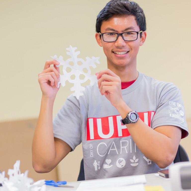 David Espiritu cuts a paper snowflake.