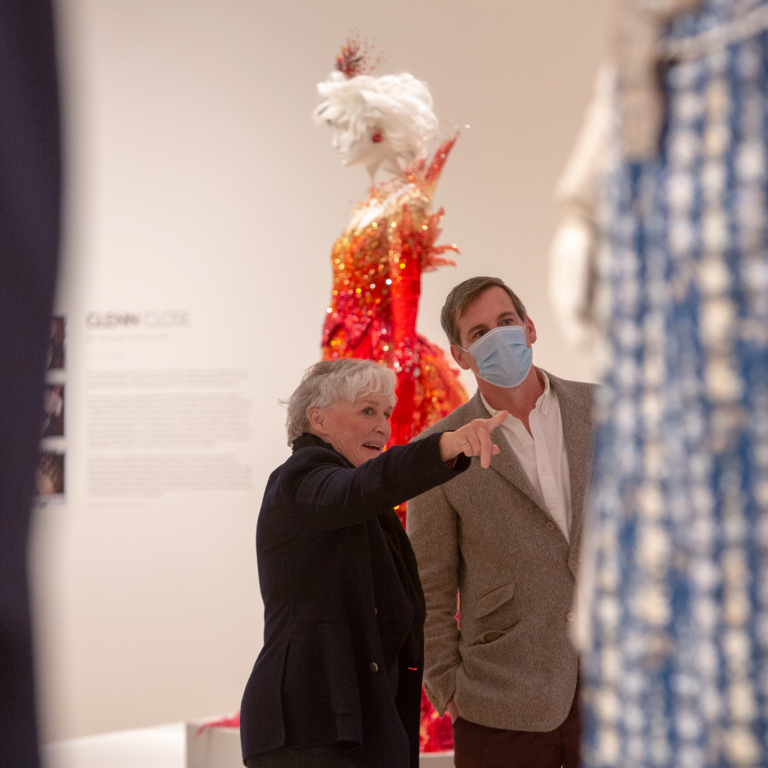 Glenn Close pointing to a costume on display
