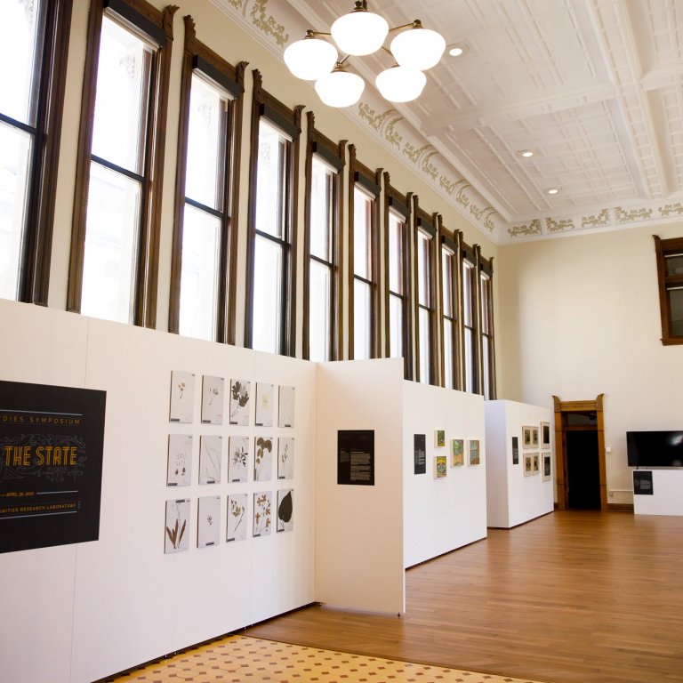 A new gallery space with art hanging on the walls and a bank of windows above it