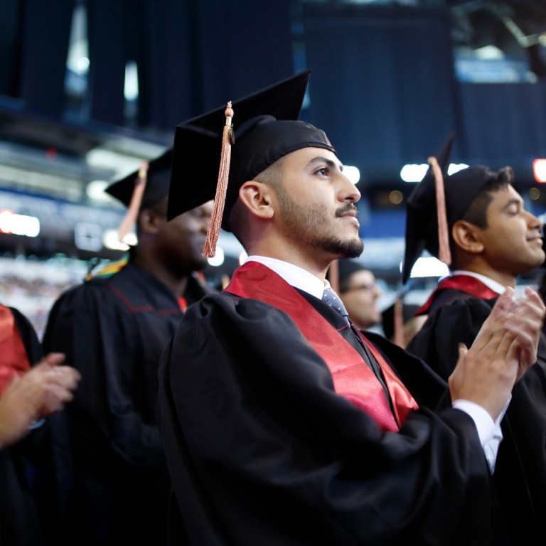 A new IUPUI graduate applauds at Commencement.
