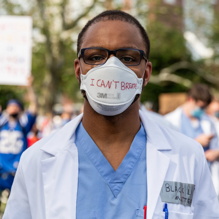 Man in a white coat wears a mask that says 'I canâ€™t breathe' on it