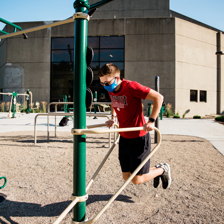 a person uses outdoor fitness equipment for dips