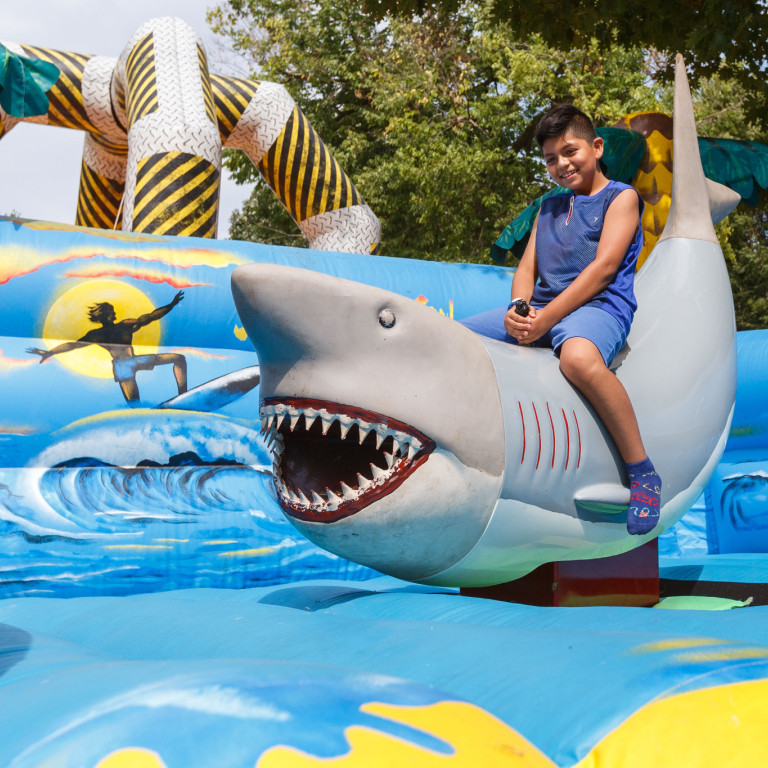 A kid sits on an inflatable shark during one of the festival games.