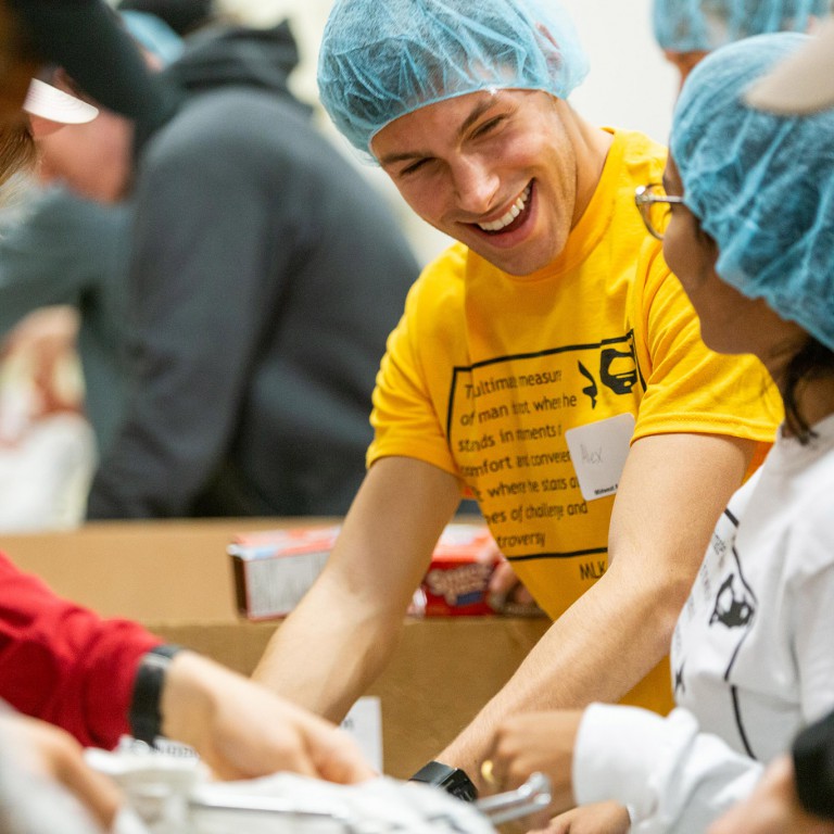 A student helps put together food packages for those in need at a food bank