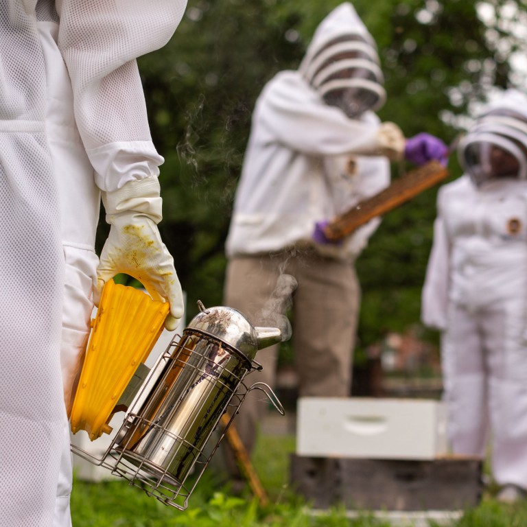 A beekeeper holds a smoker.