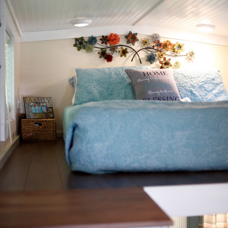 The lofted sleeping space with a blue covered bed in the home.
