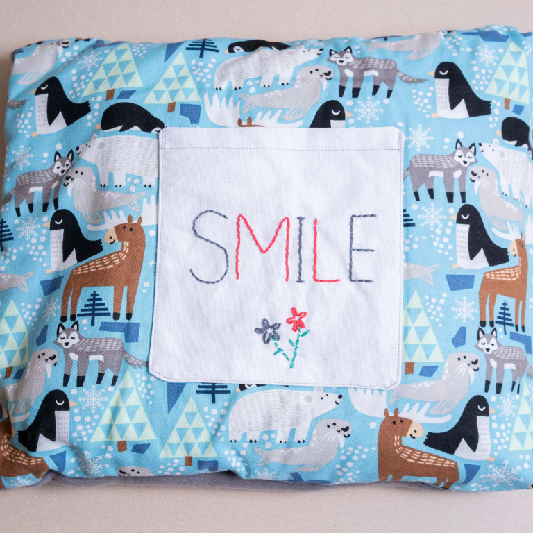 A pillow blanket with the word smile and farm animals