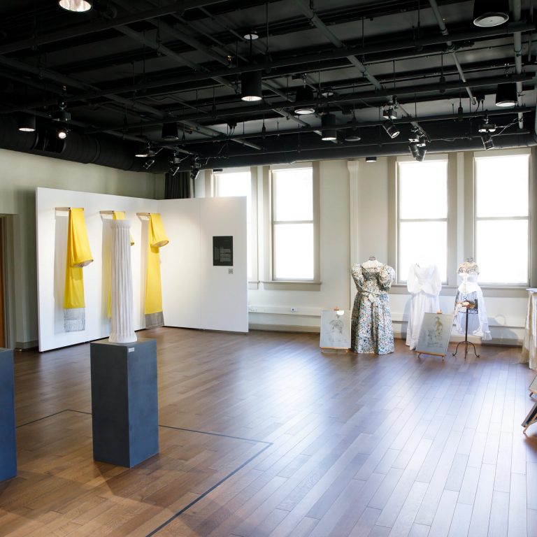 A new gallery space has paintings, sculptures and vintage dresses on mannequins