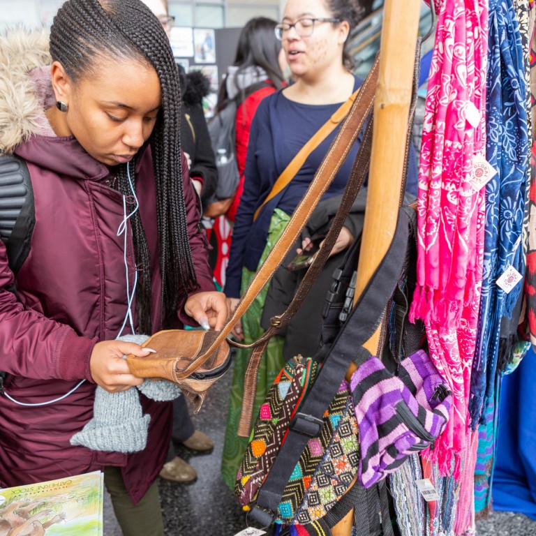 A student looks at a purse for sale at an exhibitor's booth