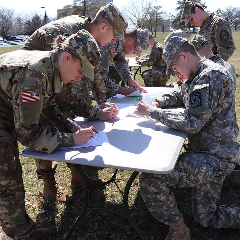 Participants stand at tables taking the written test.