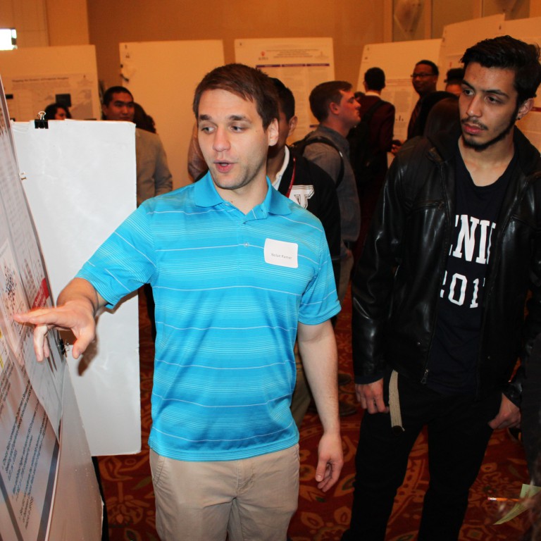 A man stands in front of a poster at IUPUI Student Research Day