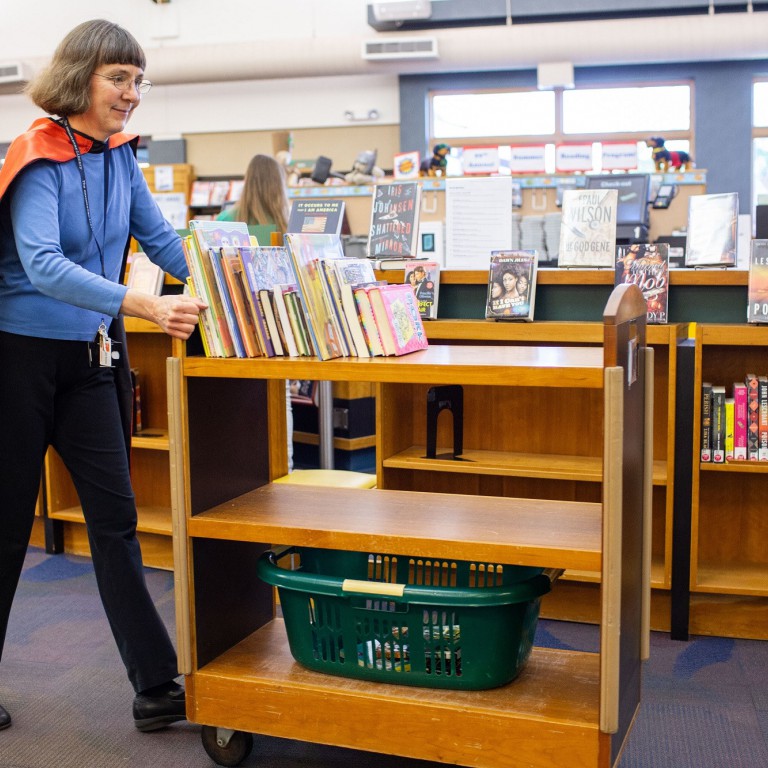 Librarian with superhero cape and cart 