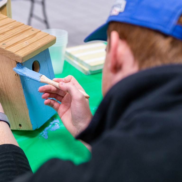 A student paints a birdhouse