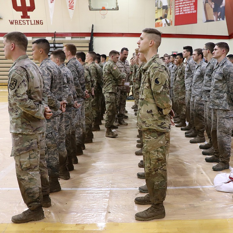 Cadets and military members stand in rows to receive their badges.