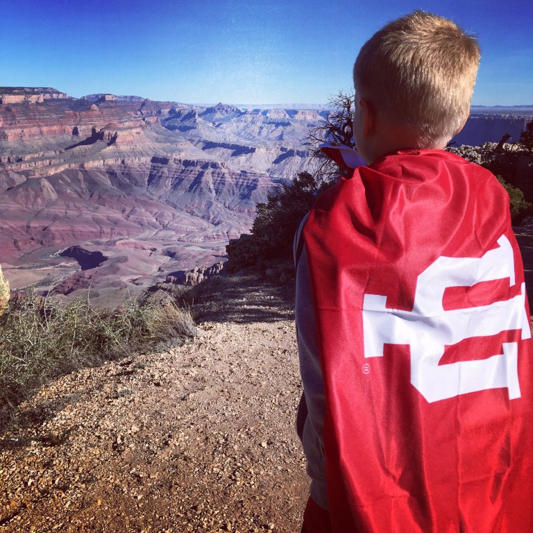 A child with an IU flag draped over his shoulders looks out over the Grand Canyon 
