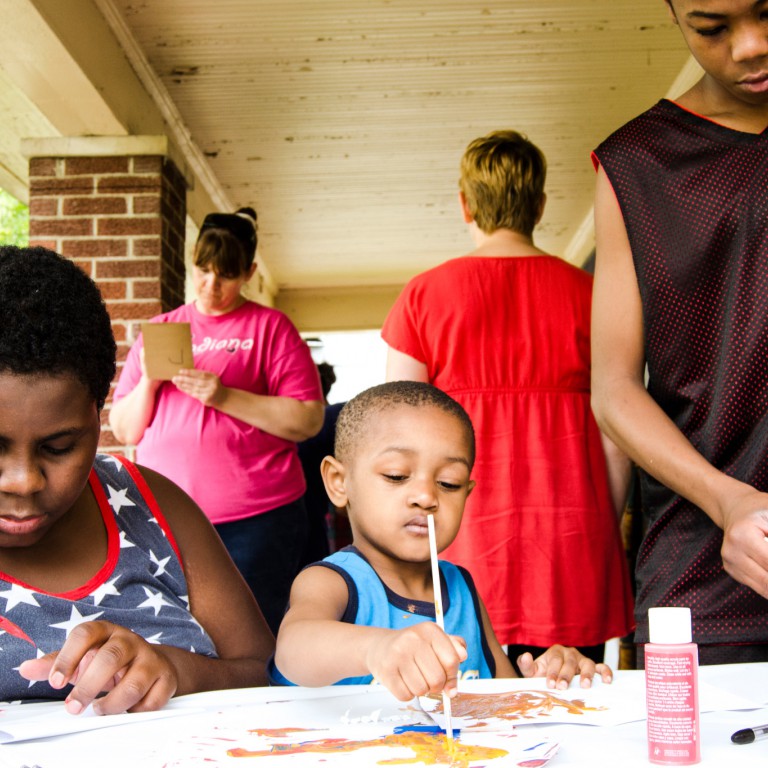 Kids practice painting at a House Life Project.