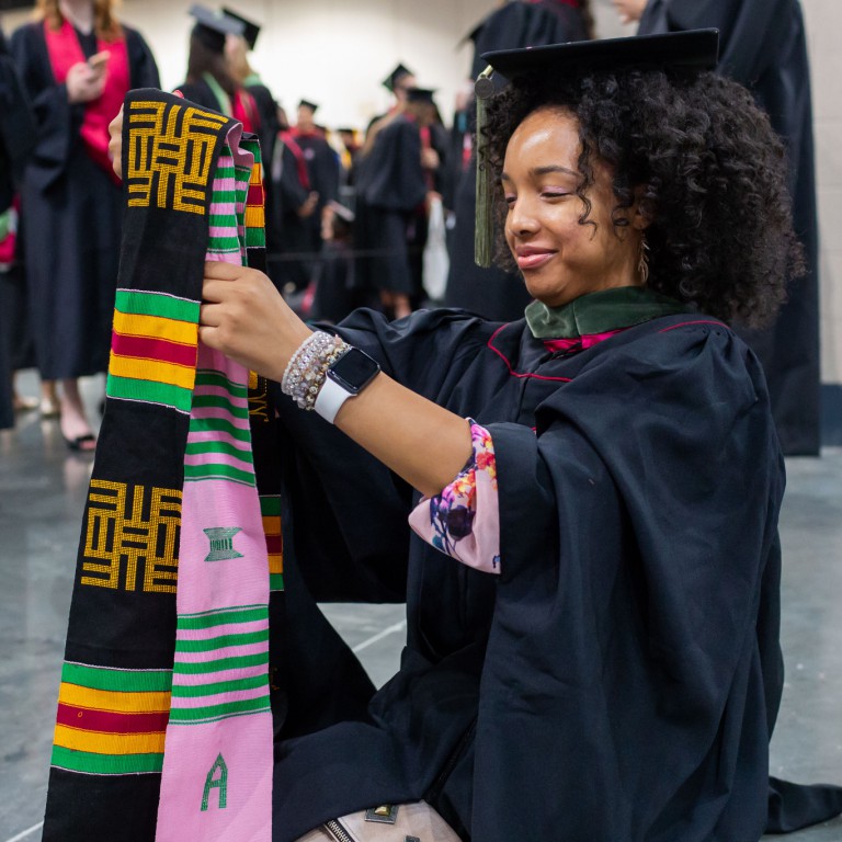 A graduate organizes her sashes at Commencement.