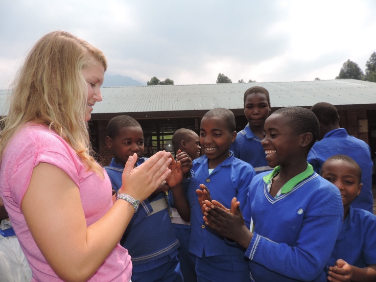 IU student Lillie Hartman plays a hand-clapping game with students from the Kabwende Primary School in Rwanda.