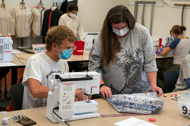 A professor checks a student's work on a tote bag