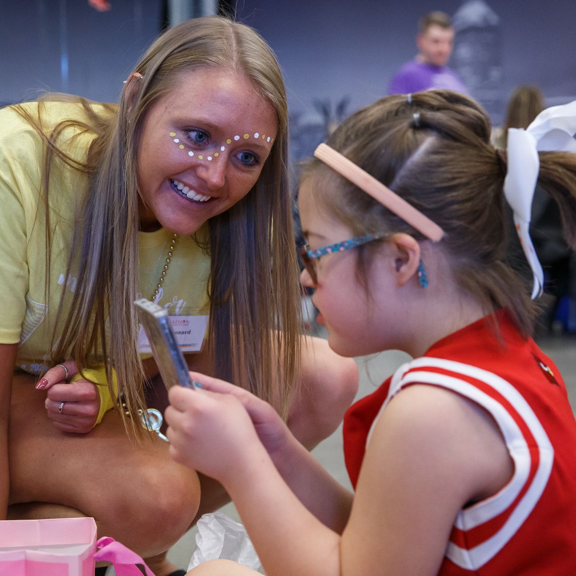 An IUPUI student wearing face paint decorations visits with a child from Riley Hospital for Children